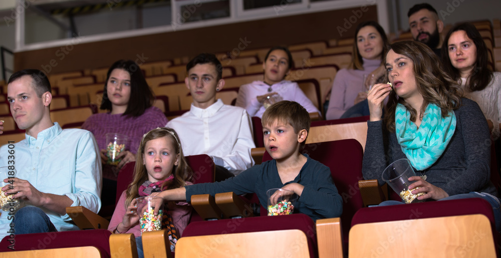 Enthusiastic audience eating popcorn and watching a movie at the cinema