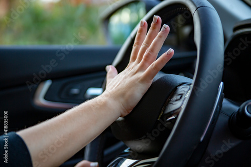 hand presses the horn on the steering wheel of a modern car, no face