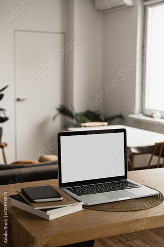 Laptop with blank copy space screen on table with notebooks on wooden table. Minimalist home office workspace. Mockup template. © Floral Deco