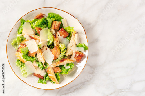 Caesar salad with grilled chicken, romaine and cheese, shot from above with a place for text