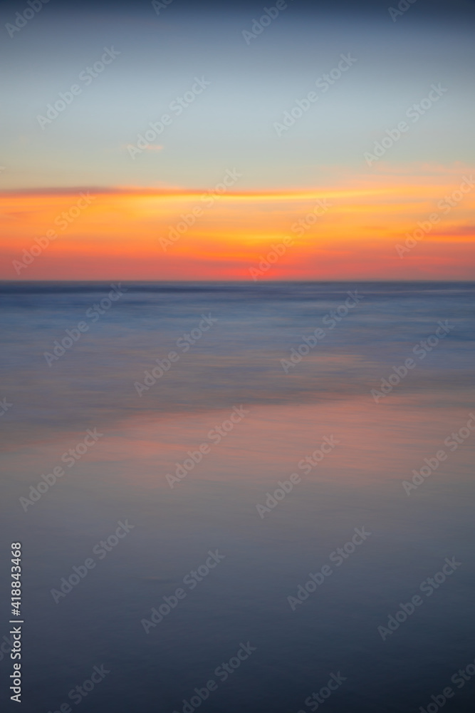 Sunset seascape. Slow shutter speed. Colorful sky. Amazing water reflection. Nature and environment background. Soft focus. Silky water. Copy space. Beach in Bali.