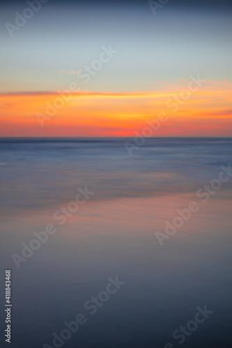 Sunset seascape. Slow shutter speed. Colorful sky. Amazing water reflection. Nature and environment background. Soft focus. Silky water. Copy space. Beach in Bali.