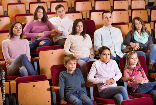 Group of positive people watching movie attentively in cinema
