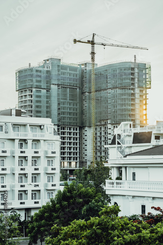 VERTICAL big multi-storey residential or office high rise building under construction, sunrise sky background, tower cranes. Real estate business, buying investing in apartments abroad, mortgage