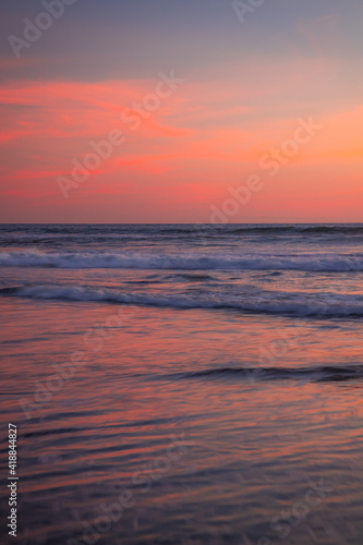 Pink sunset on the beach. Seascape for background. Colorful sky. Beautiful water reflection. Sunlight on horizon line. Nature and environment concept. Copy space. Sunset in Bali.