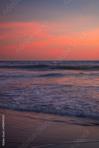 Pink sunset on the beach. Seascape for background. Colorful sky. Beautiful water reflection. Sunlight on horizon line. Nature and environment concept. Copy space. Sunset in Bali.