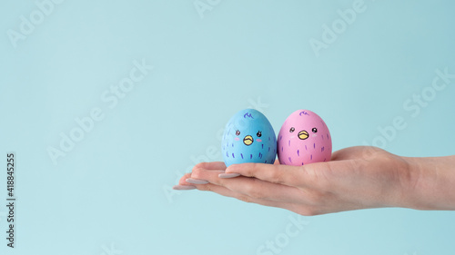 Happy relationship. Romantic date. Love partnership. Cute blue pink painted egg chicken couple with smiling face design together on female hand isolated on light conceptual empty space background.