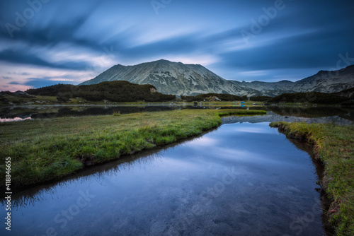 Magnificent summer panoramic view in the blue hour of the Muratovo lake and Todorka peak in Pirin Mountains