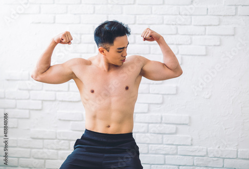 Muscular Asian young man doing exercises at home