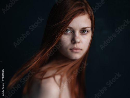 Close-up cropped view of a woman with red hair looking forward on a black background