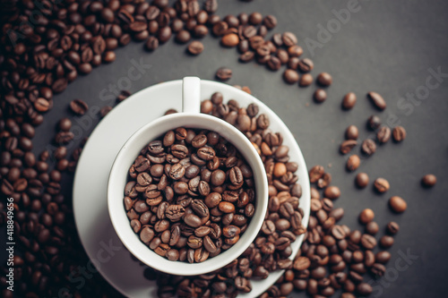 coffee beans in a cup and white saucers gray background close-up