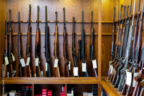 Gun shop interior with hunting and sporting rifles standing in row on display stand photo