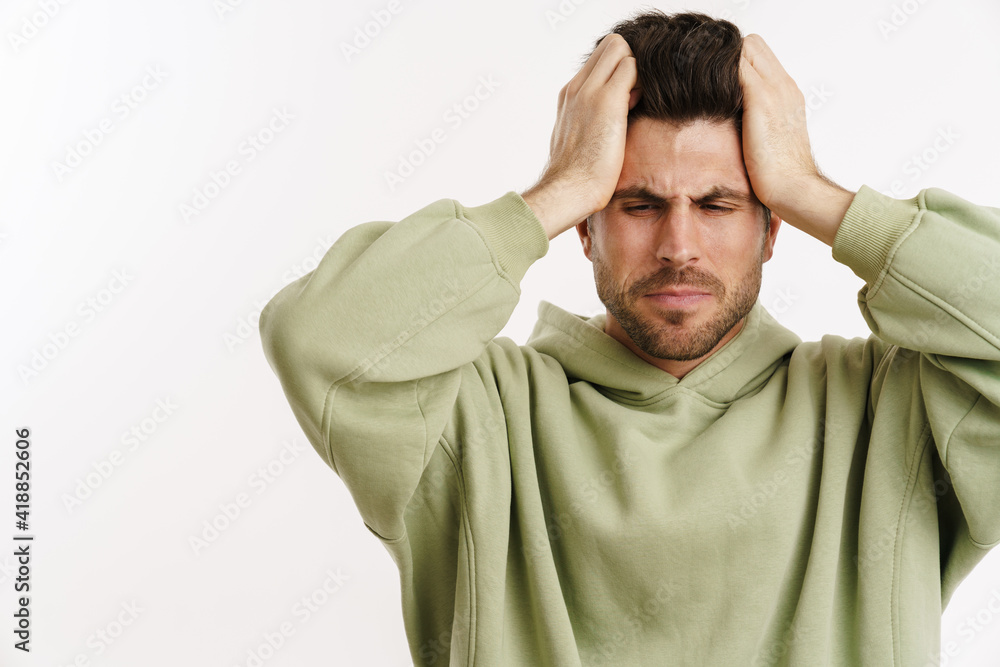 Displeased handsome man in sportswear posing and holding his head