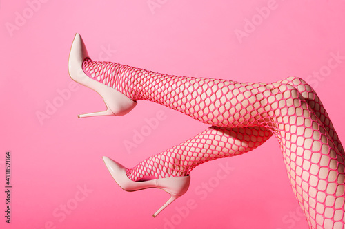 Fotografiet Female legs raised in sexy pink fishnets and high heels