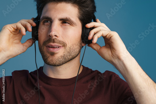 Pleased handsome man listening music with headphones