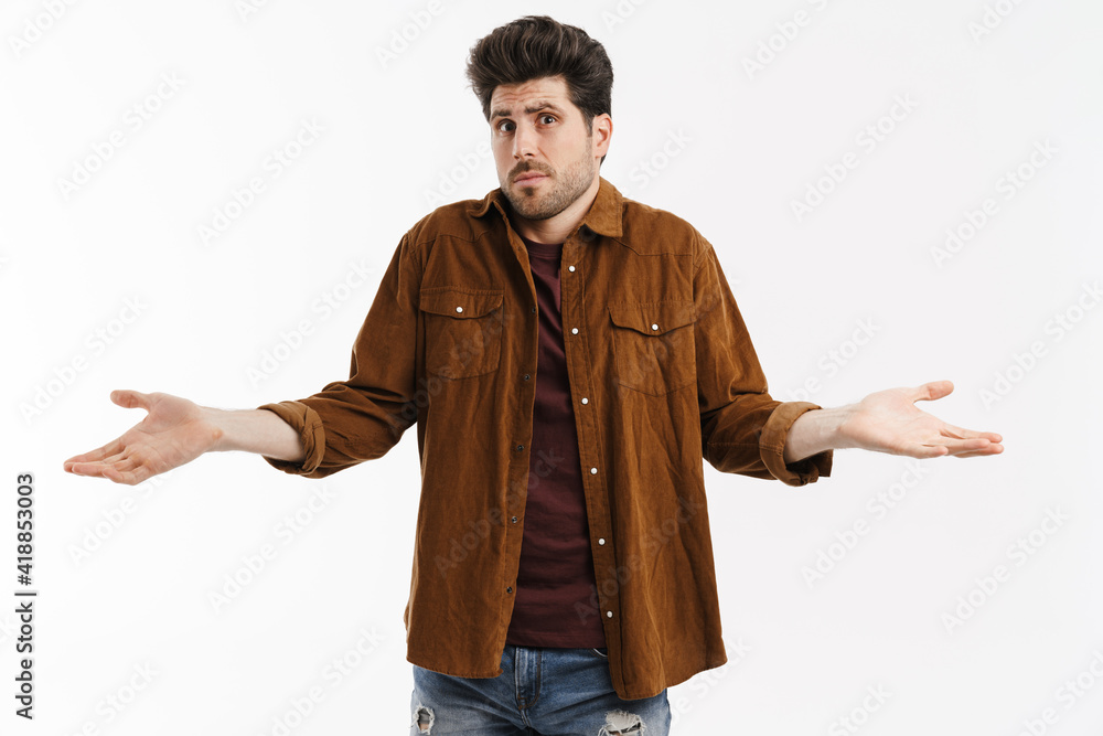 Perplexed young unshaven man showing and holding copyspace Perplexed young unshaven man showing and holding copyspace