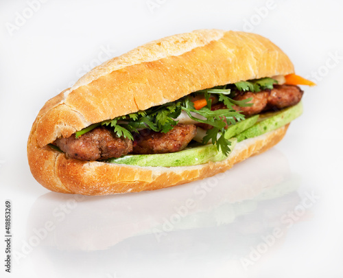 Famous Vietnamese food is banh mi thit, popular street food from bread stuffed with raw material: grilled pork and fresh herbs as scallions, coriander, carrot, cucumber, chilli. On White