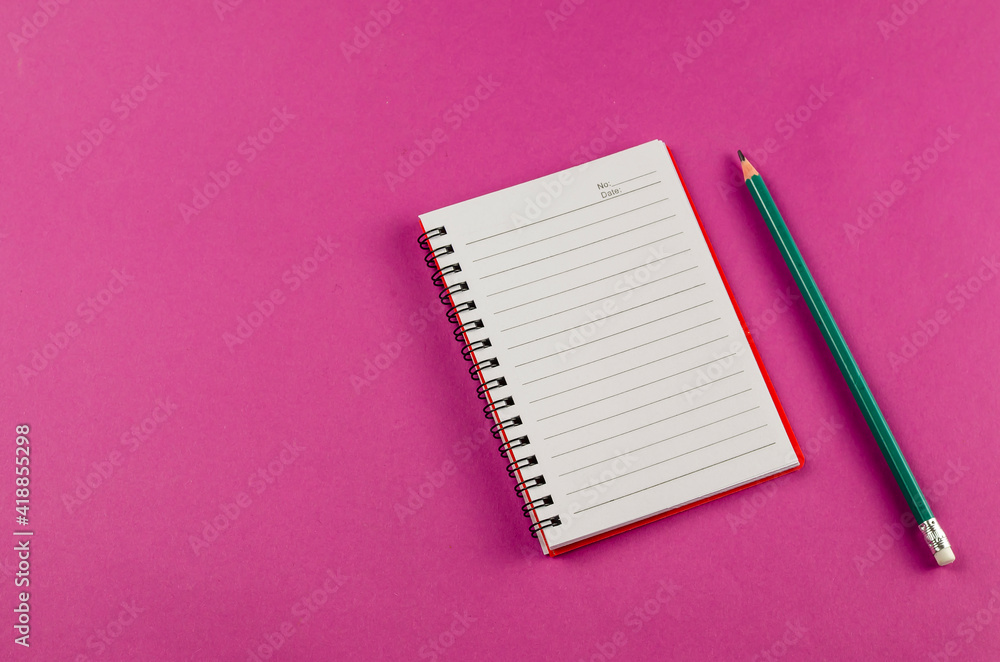 Open spring-loaded notebook and pencil on a pink background. Open spring-loaded notebook and pencil on a pink background.