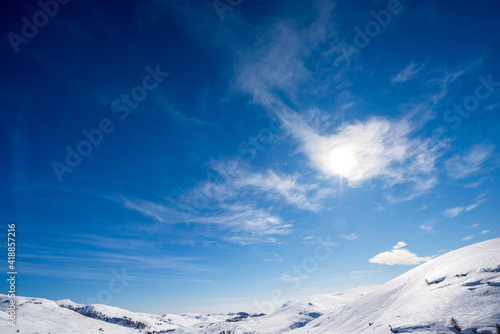 Lessinia Plateau (Altopiano della Lessinia), Regional Natural Park, in winter with snow and a beautiful blue sky with clouds and sunbeams. Malga San Giorgio ski resort, Verona, Veneto, Italy, Europe. © Alberto Masnovo
