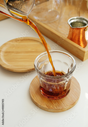 Freshly brewed pour over coffee pouring from a jug into a glass. Specialty concept photo