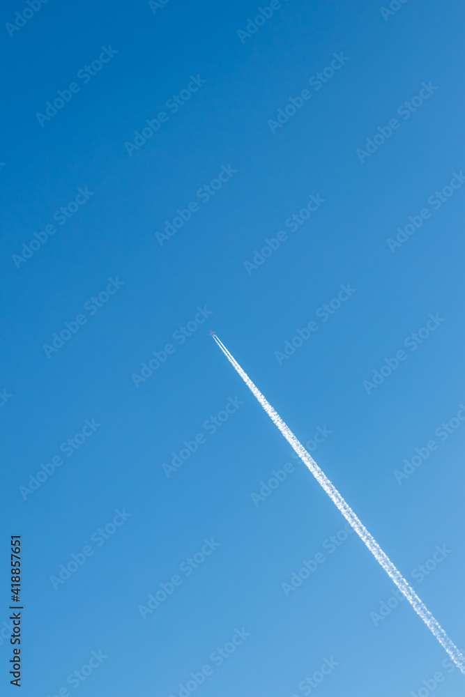 Flying airplane on a journey through the blue sky with a long white smoking exhaust plume and jetwash shows international transportation and globalization transatlantic holidays with pilots Flying airplane on a journey through the blue sky with a long white smoking exhaust plume and jetwash shows international transportation and globalization transatlantic holidays with pilots