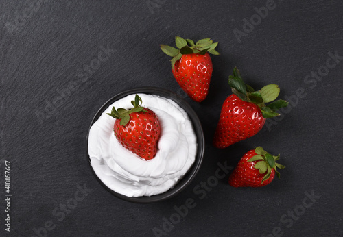 Strawberries on whipped cream on black background