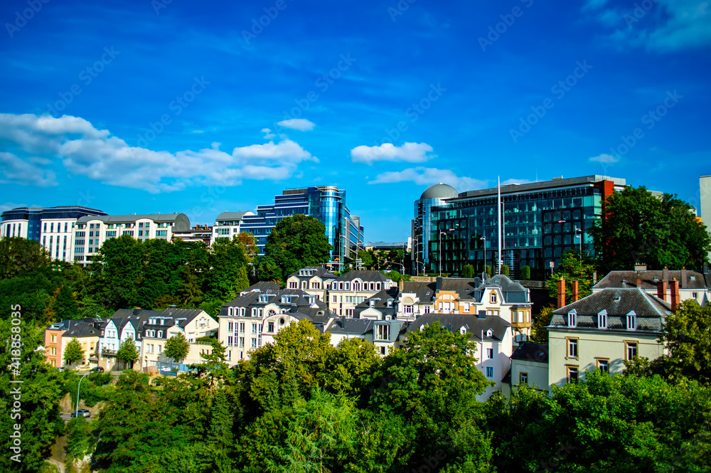 Obraz premium Luxembourg city, Luxembourg - July 15, 2019: Typical old buildings in contrast with modern glass buildings against blue sky in Luxembourg city on a summer day