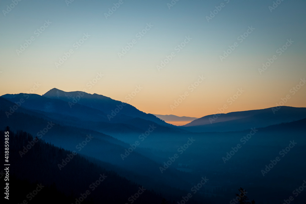 Obraz premium Night is approaching into Tatra National Park, Poland. Pastel colors of the sky and shadow covered areas in the valley. Selective focus on the ridge, blurred background.