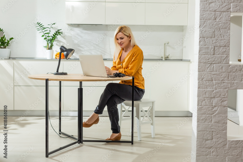 Portrait of woman working with laptop in bright kitchen. Covid-19 coronavirus. Social distancing Portrait of woman working with laptop in bright kitchen. Covid-19 coronavirus. Social distancing