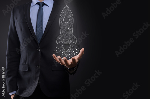 Startup business concept, Businessman holding icon transparent rocket is launching and soar flying out from screen with network connection on dark background.