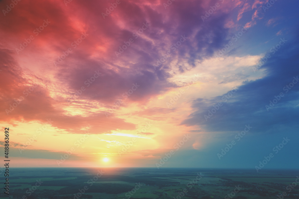 Colorful cloudy sky over the countryside at sunset. Aerial view of the countryside in the evening