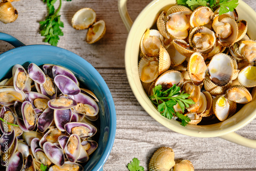 Two pots photographed from above, one blue with tellerinas and one white beige with cockles with parsley and cloves of decoration on an elegant gray rustic background photo