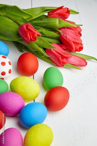 Easter Eggs and red tulip flowers on white wooden table