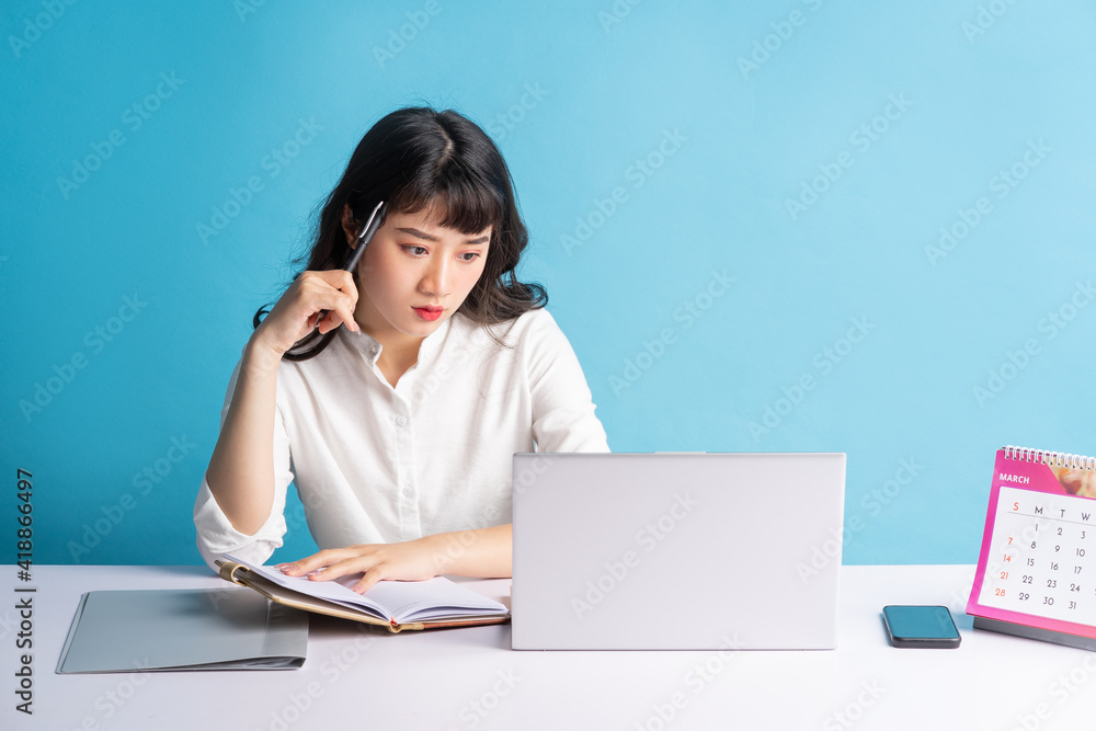 Young Asian buisness woman working on blue background Young Asian buisness woman working on blue background
