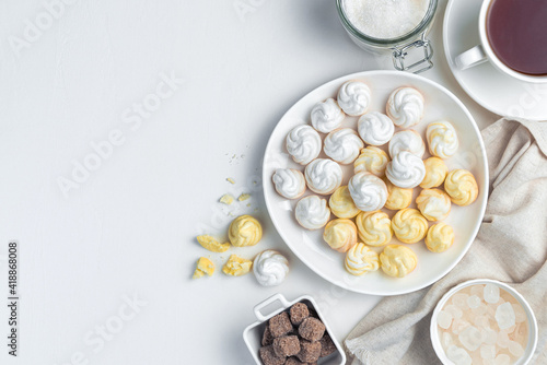 Sweet, airy meringues in white and yellow, with a cup of tea.