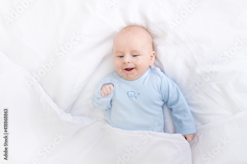 laughing baby boy on the bed under the blanket, healthy sleep baby
