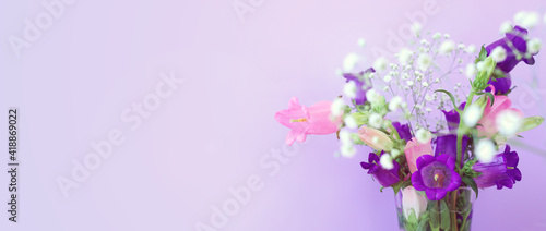 spring bouquet of purple and pink bell flowers over purple wooden background