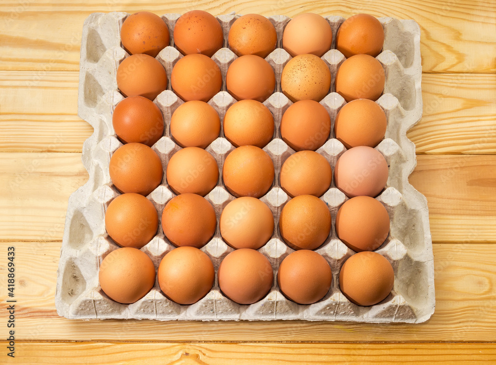 Brown eggs in cardboard egg tray on wooden rustic table Brown eggs in cardboard egg tray on wooden rustic table