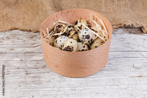 Quail eggs in small wooden box on old wooden surface