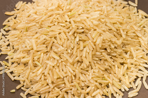 Pile of uncooked brown rice on brown dish close-up