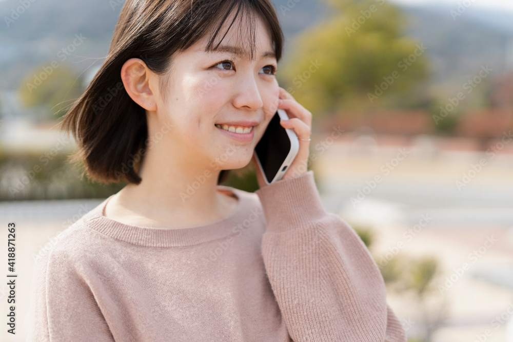公園でスマートフォンを使う女性 公園でスマートフォンを使う女性