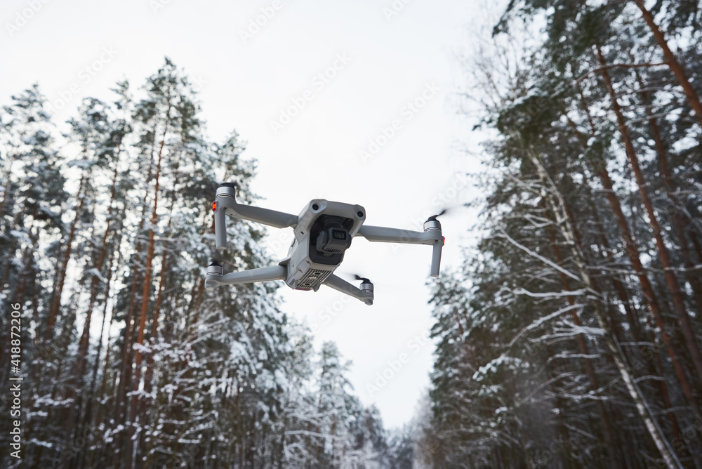 Drone quadcopter with camera flying in winter forest Drone quadcopter with camera flying in winter forest