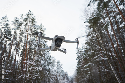Drone quadcopter with camera flying in winter forest