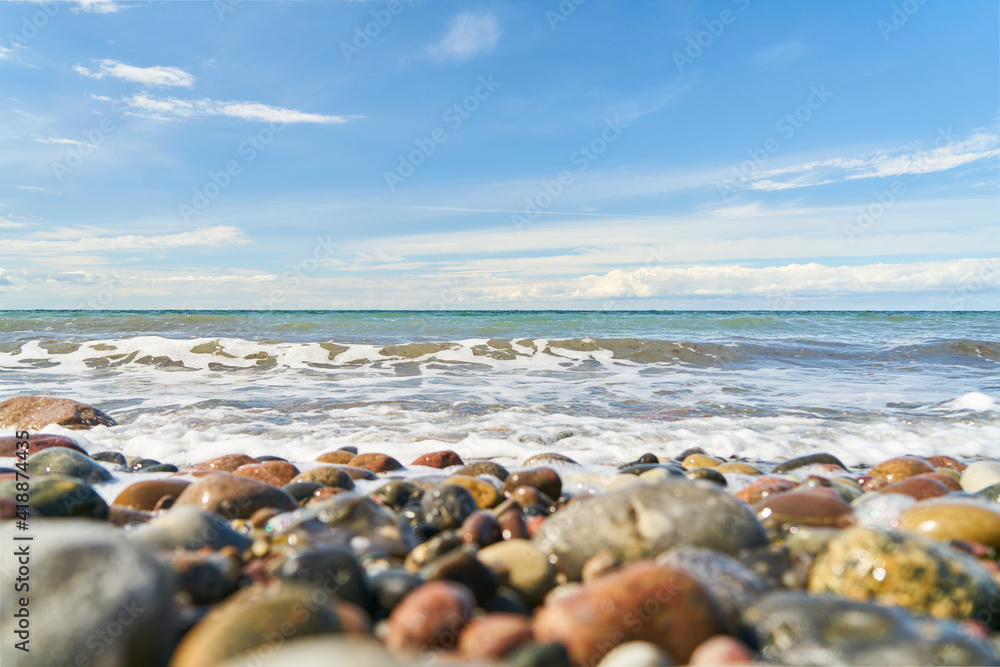 Pebbles on the beach by the sea with waves and sky Pebbles on the beach by the sea with waves and sky