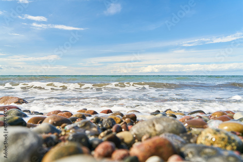 Fototapeta Naklejka Na Ścianę i Meble -  Pebbles on the beach by the sea with waves and sky