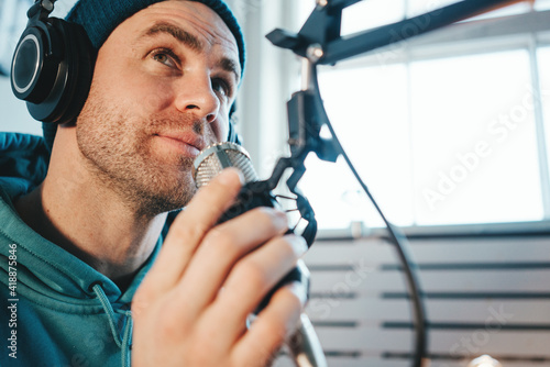 Young host streaming his audio podcast at home broadcast studio