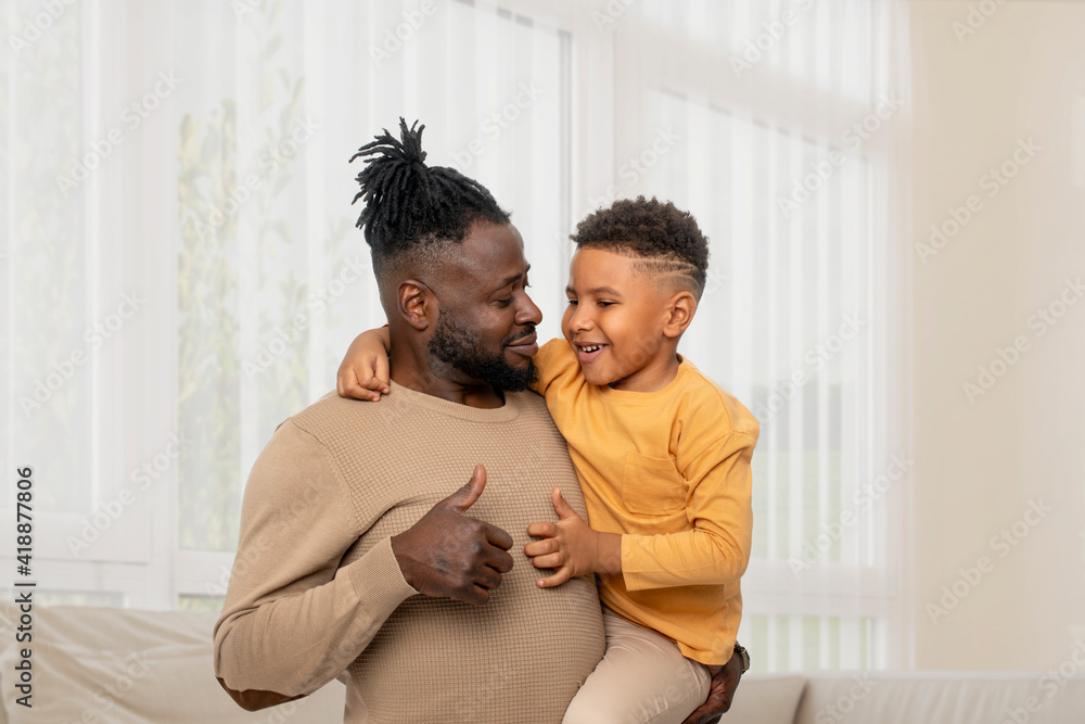 Dark skinned African male with little son spending time at home together Dark skinned African male with little son spending time at home together