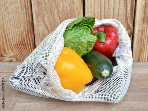 fresh vegetables in a reusable bag put on a wooden table