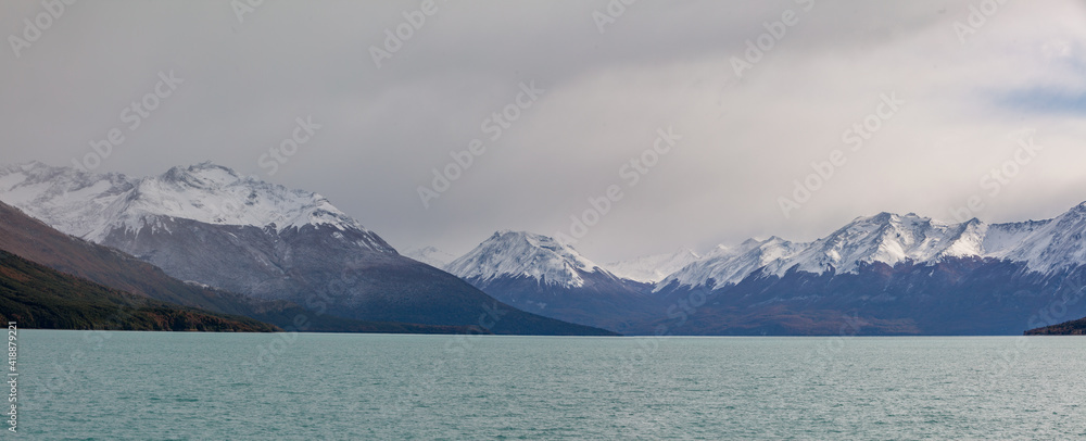 Panoramic view of the lake Lago Argentino with snow covered mountains in the background under overcast sky