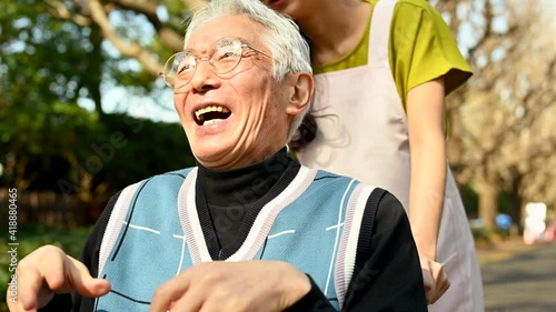 楽しそうに外を散歩する車椅子に乗った高齢者と女性福祉士	
 photo